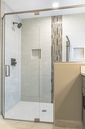 Newly remodeled shower showing a euro glass shower door and a half wall with glass on top.