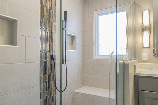Walk in tile shower with mosaic glass column and slide bar in this bathroom remodel from Shelby Township.